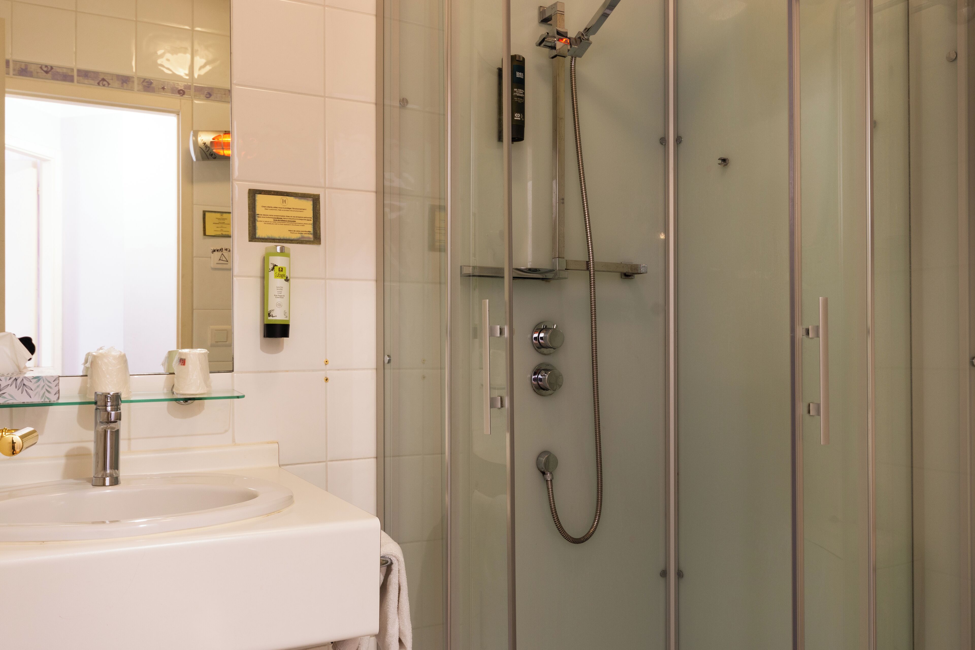 A bathroom with a glass-enclosed shower, a white sink, and a mirror above the sink.