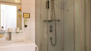 A bathroom with a glass-enclosed shower, a white sink, and a mirror above the sink.