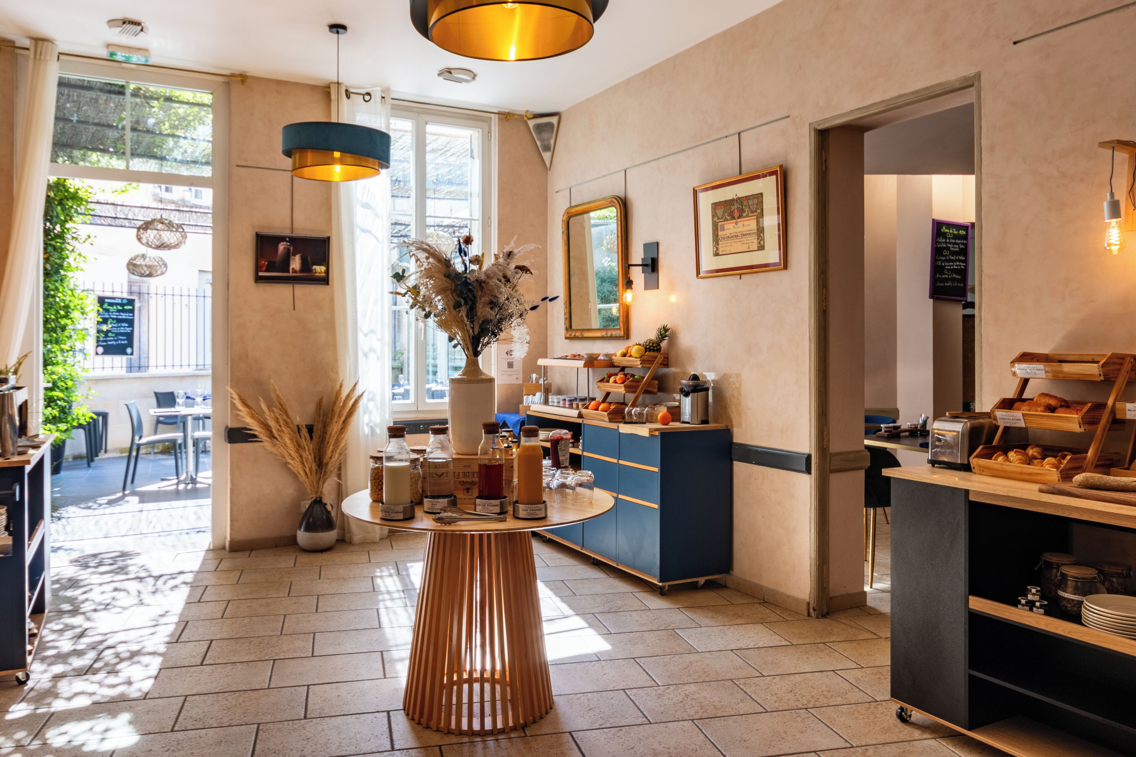 Een moderne café met een houten tafel, een vaas met gedroogde planten, een koffiemachine en een toonbank met brood en gebak.