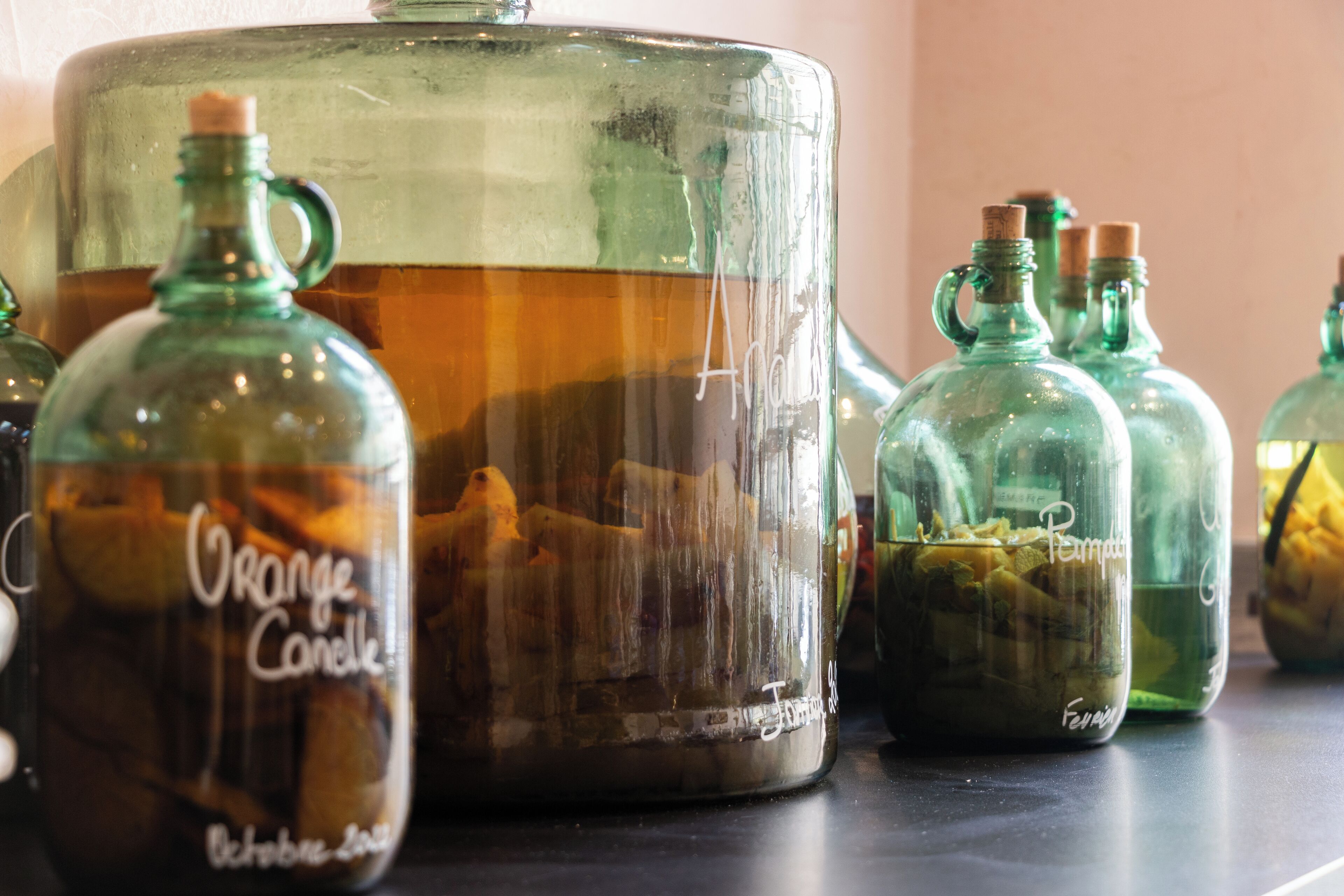 Un ensemble de récipients en verre, chacun portant une étiquette, et dont certains contiennent des parfums d’orange et de potiron, disposés sur une surface.