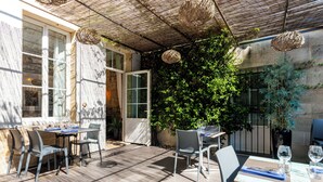An outdoor patio with tables and chairs, a pergola, and a wall covered in greenery. - Hôtel de la tour à LIBOURNE (Libourne)