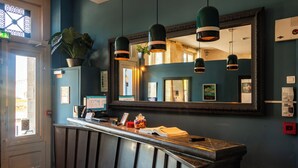 A reception area with a counter, a large mirror, pendant lights, and a potted plant. - Hôtel de la tour à LIBOURNE (Libourne)