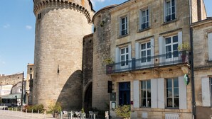 A historic stone tower adjacent to a building with multiple windows and balconies. - Hôtel de la tour à LIBOURNE (Libourne)