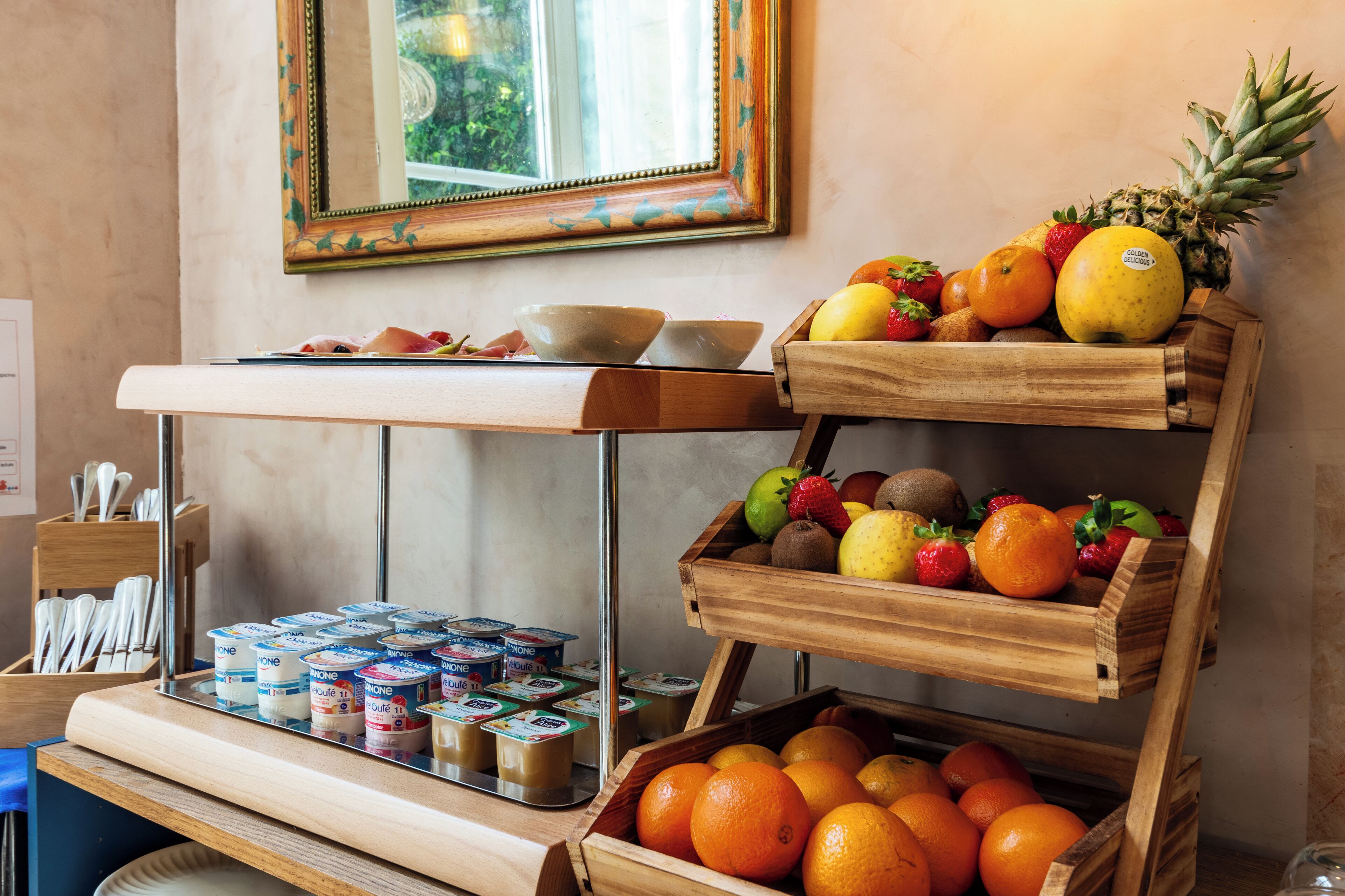 Een ontbijtbuffet met yoghurt, fruit en een spiegel.
