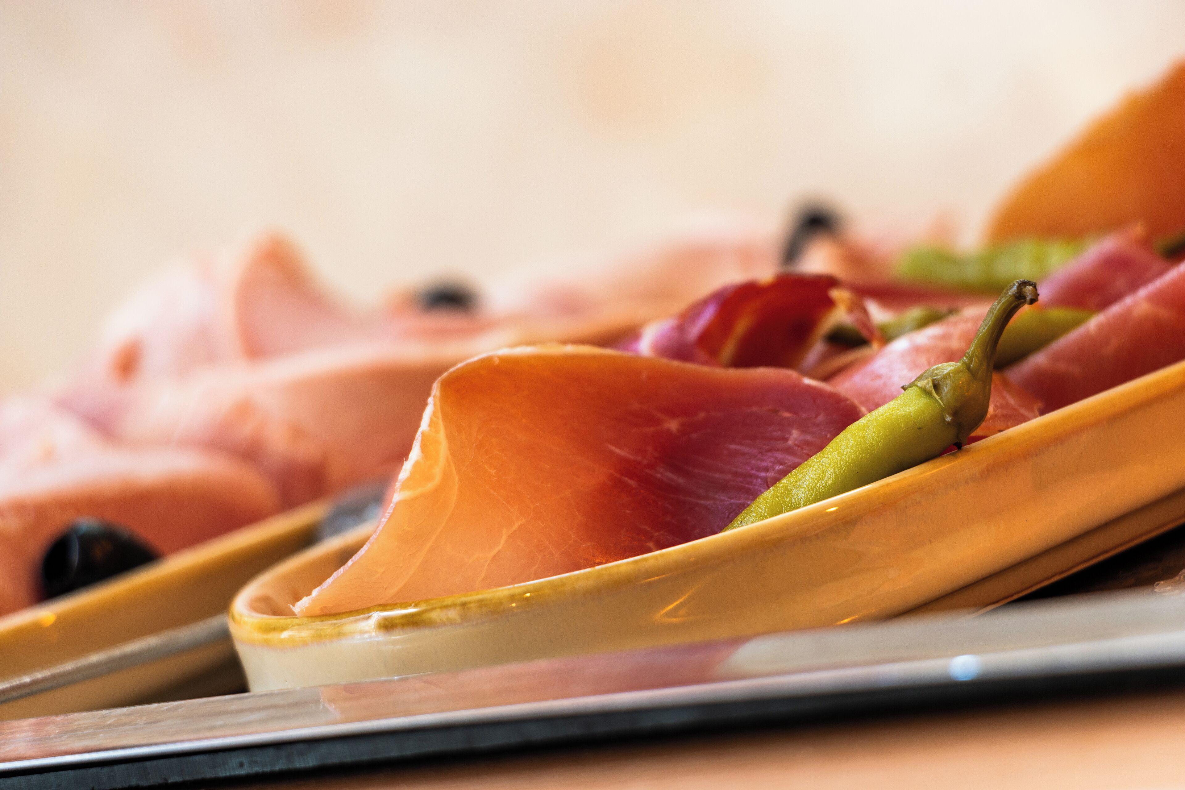 Un plato con diversos embutidos y aceitunas.