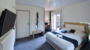 Een hotelkamer met een bed, een bureau, een stoel, een televisie en een raam.