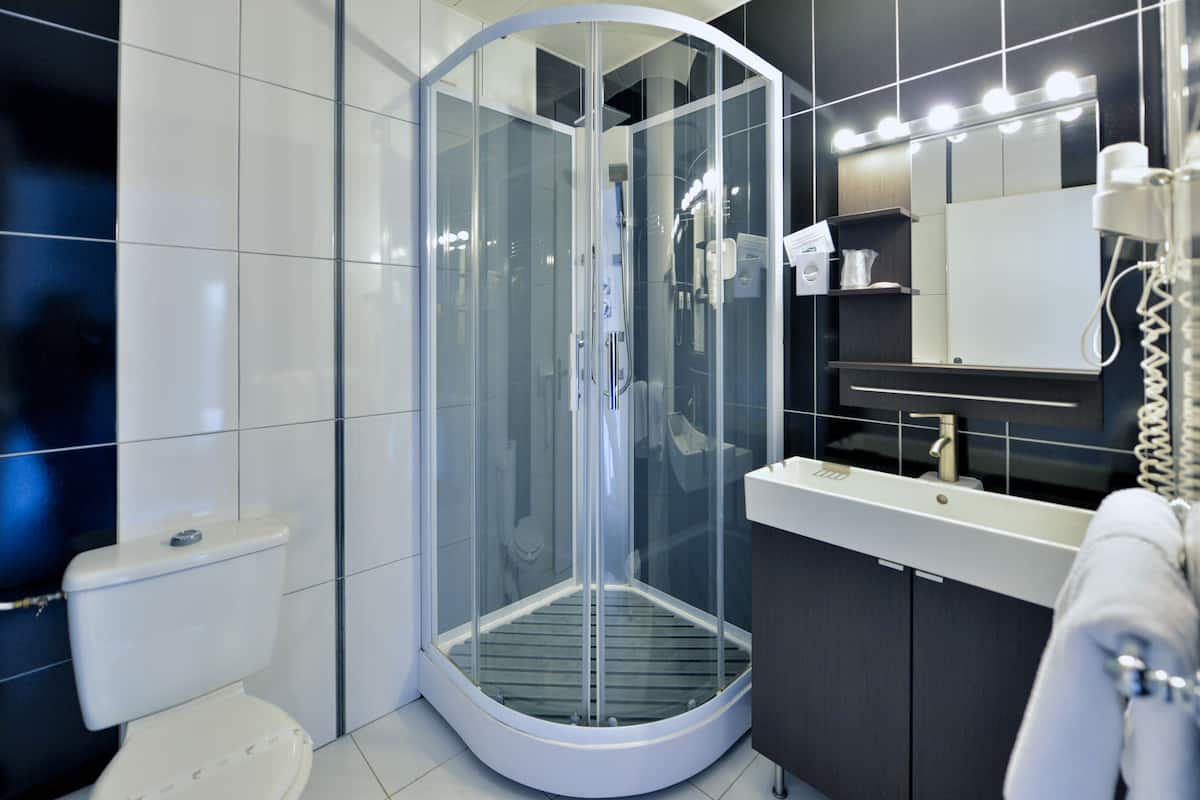 Een moderne badkamer met een douchecabine van glas, een toilet en een wastafel met spiegel en wasbak.