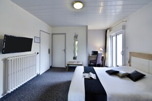 A hotel room with a bed, a desk with a chair, a television mounted on the wall, and a window with curtains. - Contact Hôtel le Moulin Neuf (Chantonnay)