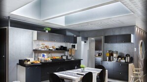Una cocina moderna con armarios oscuros, una isla central y un comedor con mesa y sillas.