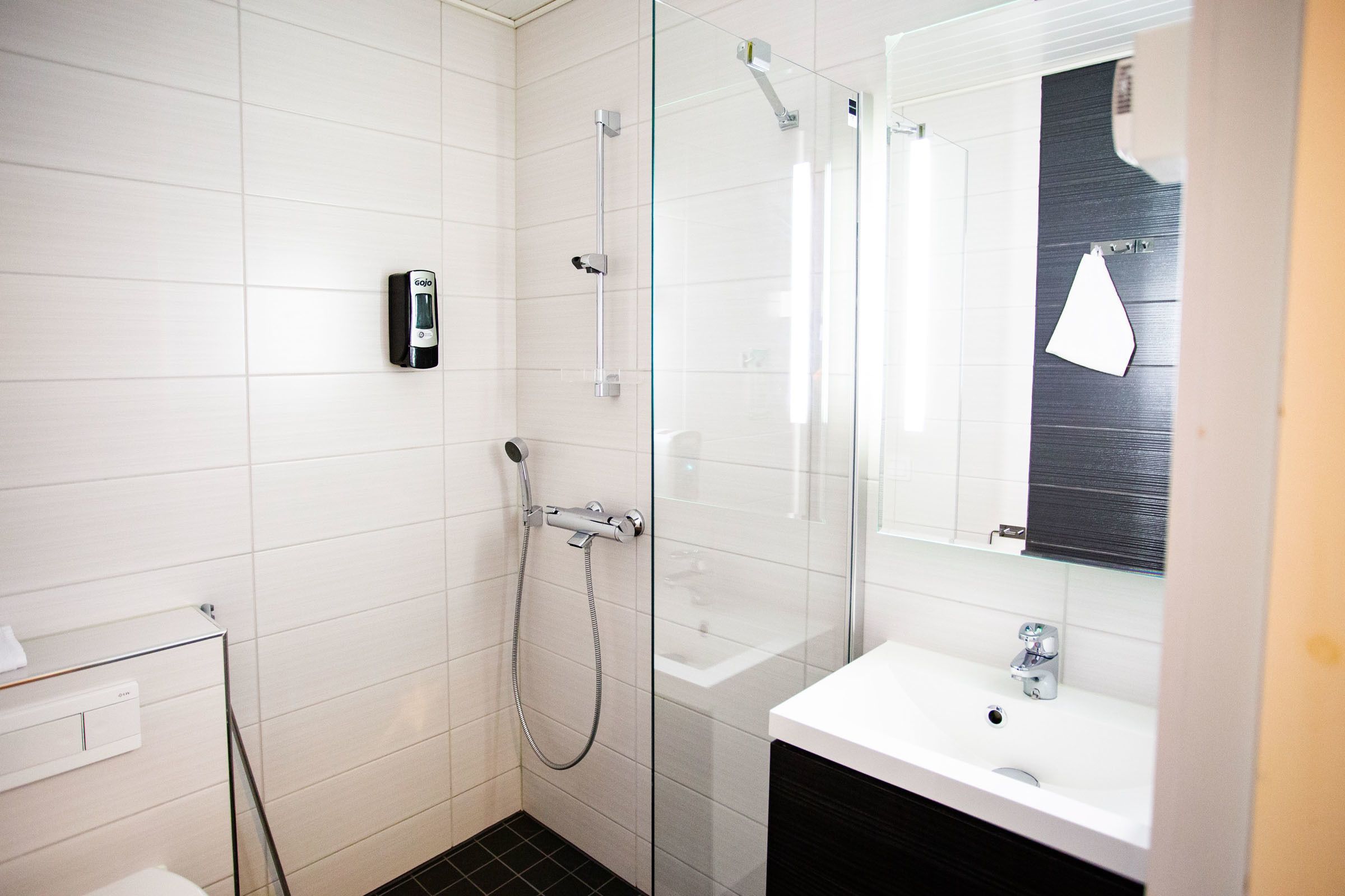 A modern bathroom with a glass shower enclosure, a white sink, and a handheld showerhead.