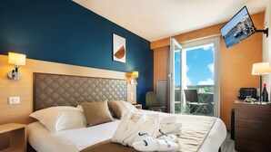 Una habitación de hotel con una cama, televisión, escritorio y vistas al exterior.