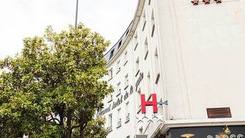 Een hotel met een opvallend bord 'Grand Hotel de la Gare', een 'Brass' gevel en terras met parasols.