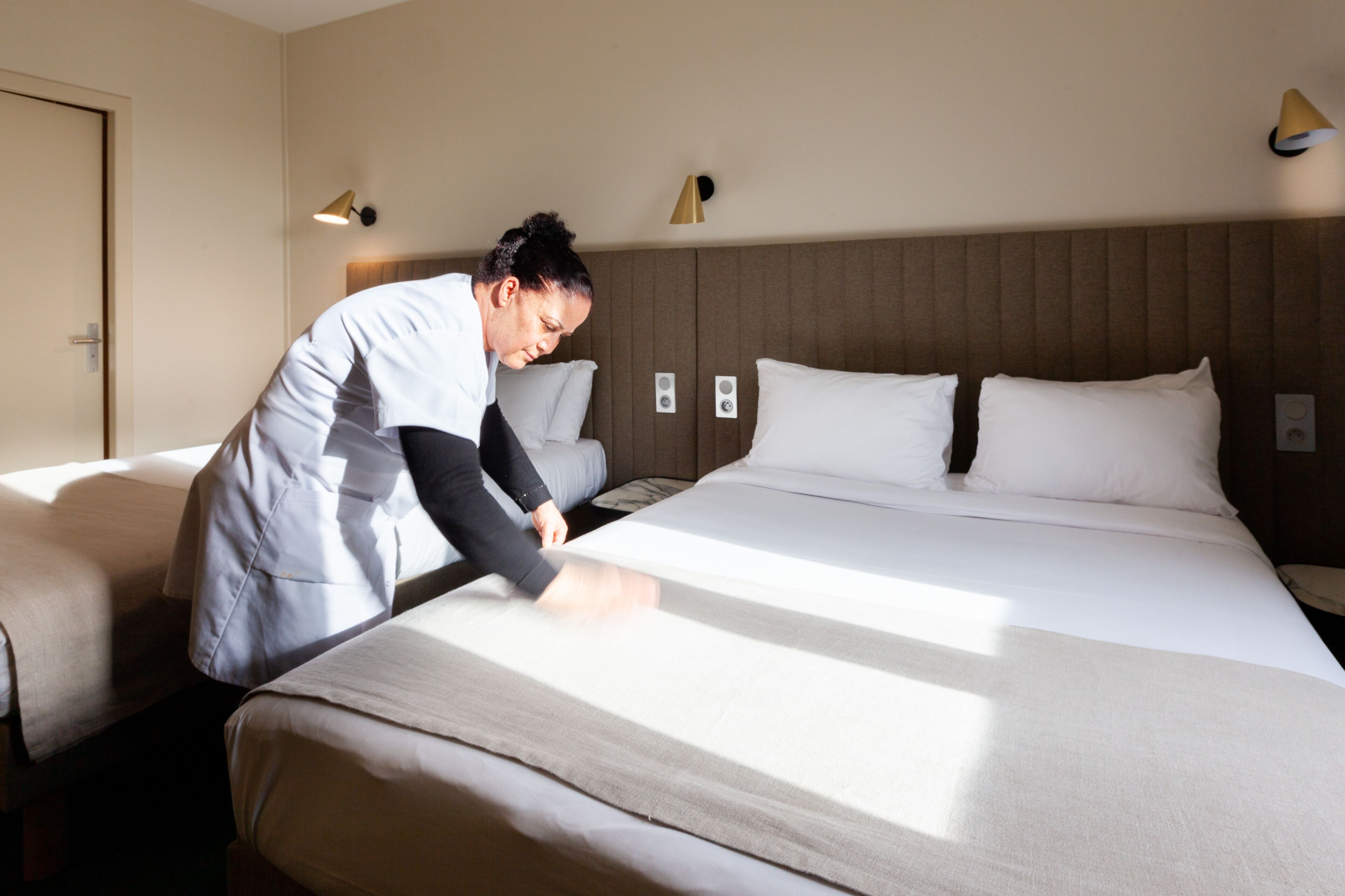 A hotel room with a large bed, two bedside tables, and a wall-mounted lamp.