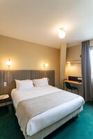 Habitación de hotel con cama grande, mesita de noche y escritorio con silla.