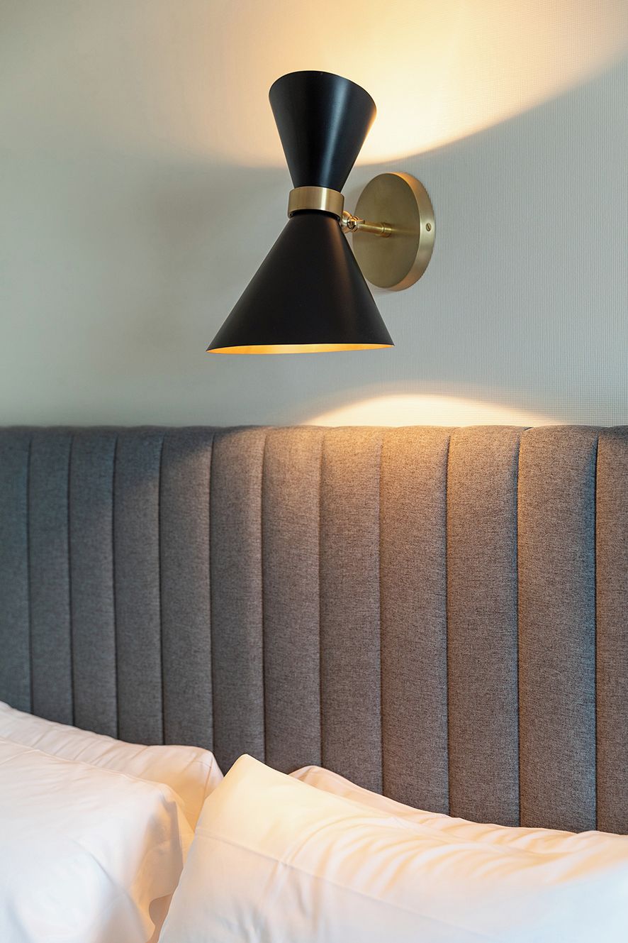 A bed with a grey upholstered headboard and white bedding.