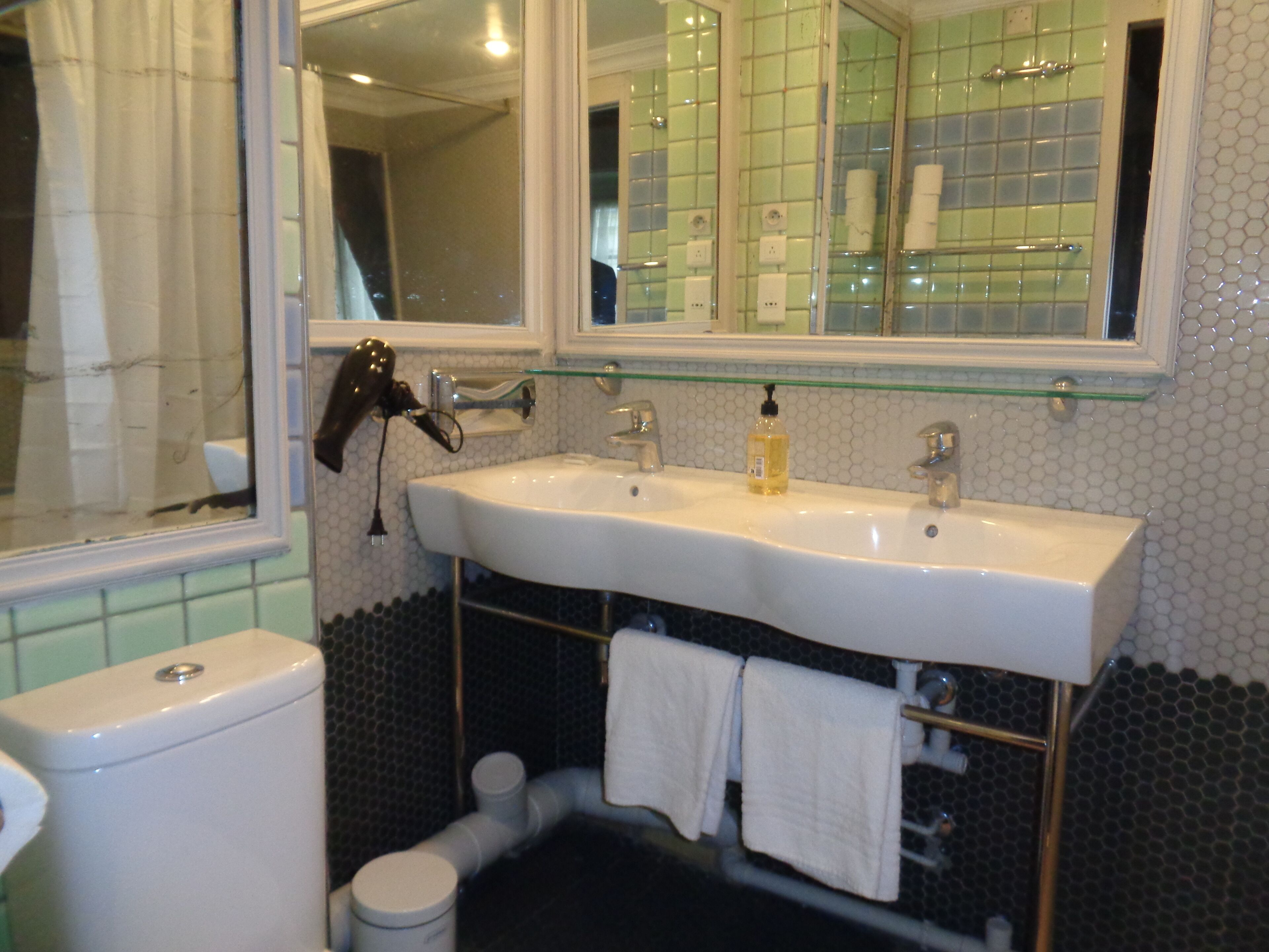 A bathroom with a white sink, a mirror, and a glass shelf above the sink.
