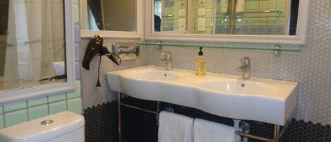 A bathroom with a white sink, a mirror, and a glass shelf above the sink.