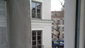 Vista de um edifício com várias janelas e varandas, uma rua com uma bicicleta e uma placa de proibido estacionar.