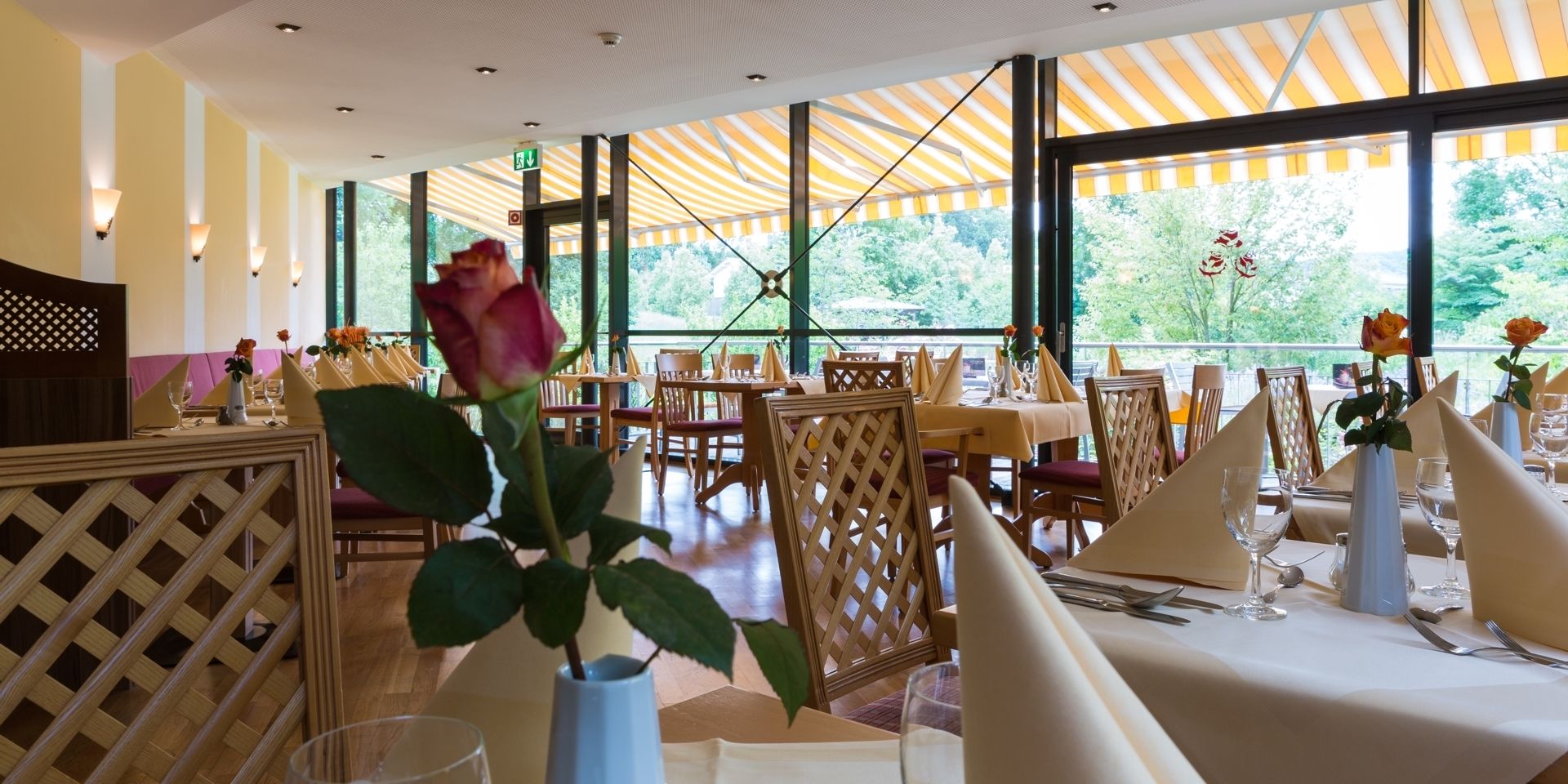 A restaurant with tables set for dining, featuring a view through large windows.