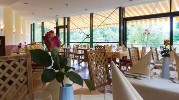 A restaurant with tables set for dining, featuring a view through large windows.