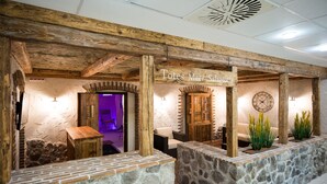 A rustic interior with exposed wooden beams, stone walls, and a sign reading "Totes Meer Salzgrotte."
