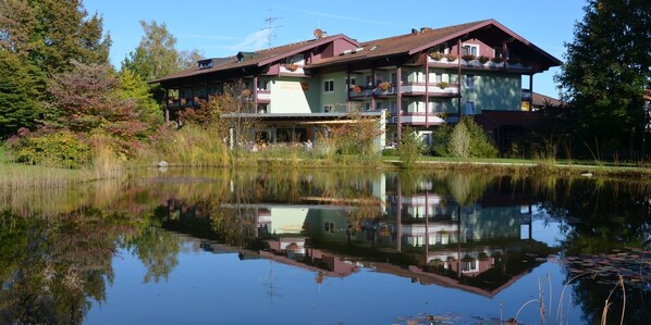 Ein großes, mehrgeschossiges Gebäude mit Balkonen und Spiegelung im Wasser.