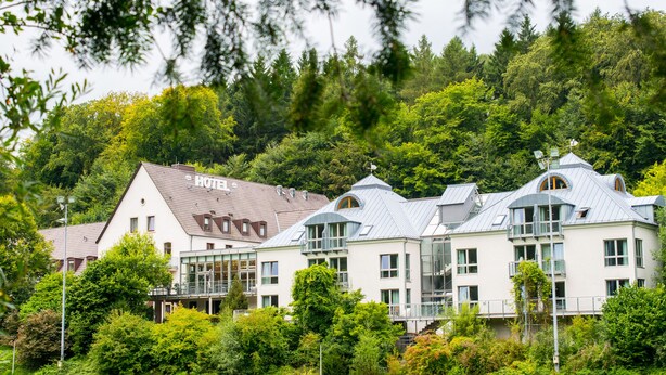 A hotel with multiple buildings, surrounded by lush greenery and trees.