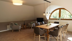 A dining area with a wooden table and chairs, a sofa, and a TV.