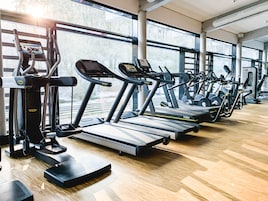 Un gimnasio con cintas de correr, elípticas y máquinas de pesas.