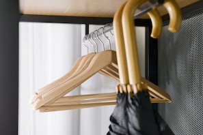 A wooden coat rack with a black plastic bag hanging on it. - AMC Hotel - Schöneberg (Berlin)