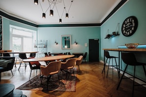 A modern dining area with a wooden table, cushioned chairs, and a herringbone-patterned rug. - AMC Hotel - Schöneberg (Berlin)