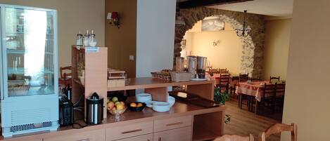 A dining area with wooden furniture, a buffet setup, and a stone wall.