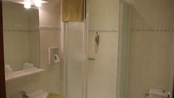 Un baño con ducha de vidrio, lavamanos con toalla y retrete.