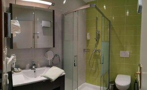 Une salle de bain moderne avec une douche à parois de verre, un lavabo blanc et des toilettes.
