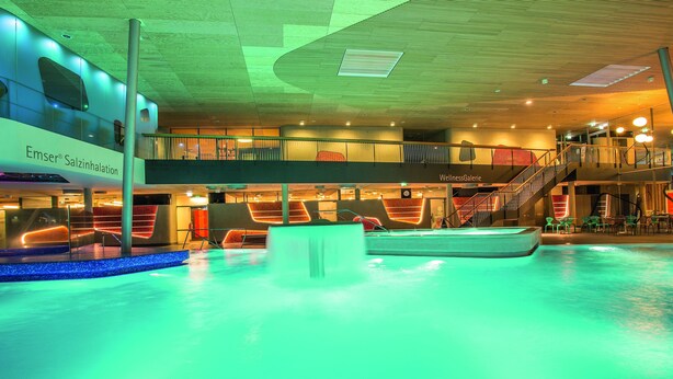 A multi-level indoor swimming pool with a modern design, including a visible staircase and lounge area. - BSW - Hotel Lindenbach (Nievern)