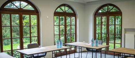 Un salón de conferencias con ventanas arqueadas, una larga mesa y sillas.