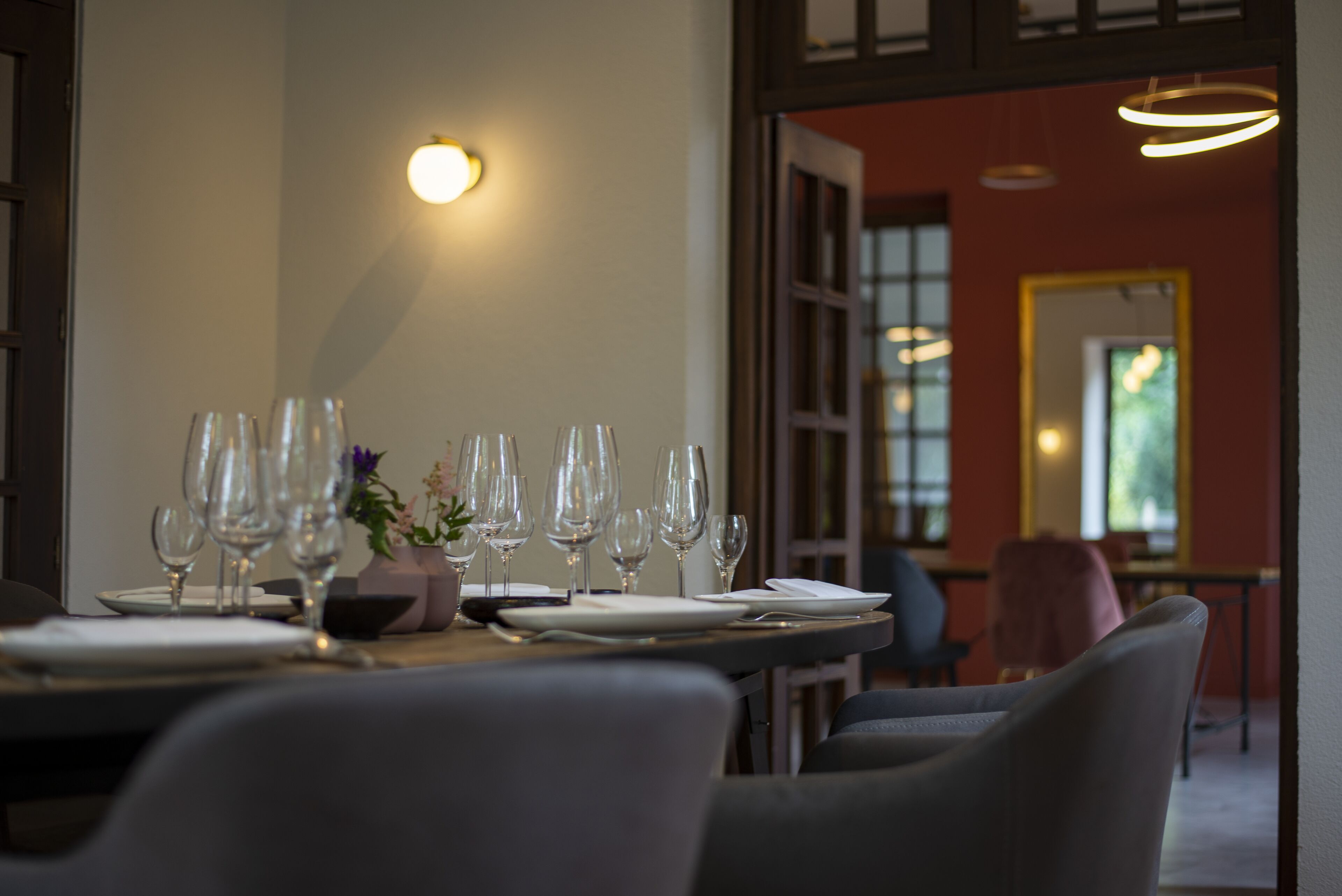 A dining area with a table set for a meal, chairs, and a vase with flowers.