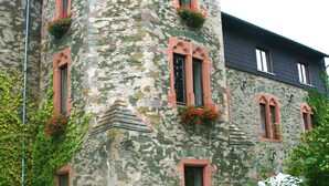 A stone building with multiple windows, some with flower boxes, and outdoor seating with umbrellas. - Schlosshotel Braunfels (Braunfels)