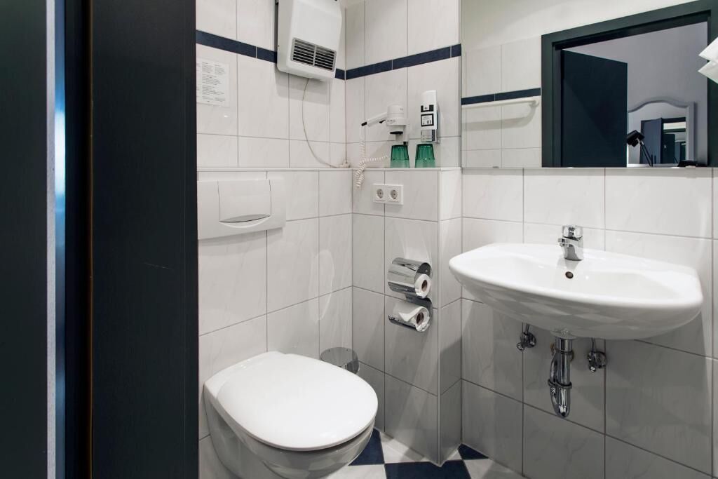 A small bathroom with a toilet, a sink, and a mirror.