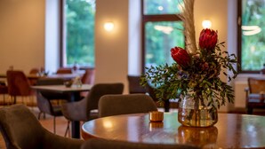 A dining area with round tables, chairs, and a vase with red flowers on one table. - Schlosshotel Braunfels (Braunfels)