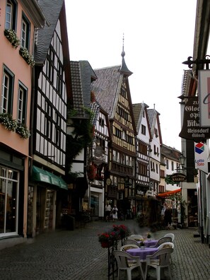 A cobblestone street lined with traditional half-timbered buildings, some with visible signage indicating local businesses. - Hotel Kurhaus Uhlenberg (Bad Muenstereifel)