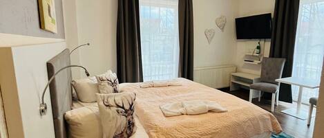 Une chambre d’hôtel bien aménagée, avec un grand lit, un bureau et un téléviseur.