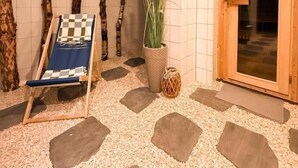Un espace de détente avec un fauteuil à motifs à carreaux, une plante en pot et une porte en bois.