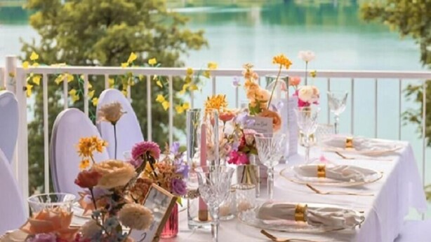 Une table dressée pour un repas, avec vue sur un lac et des arbres.