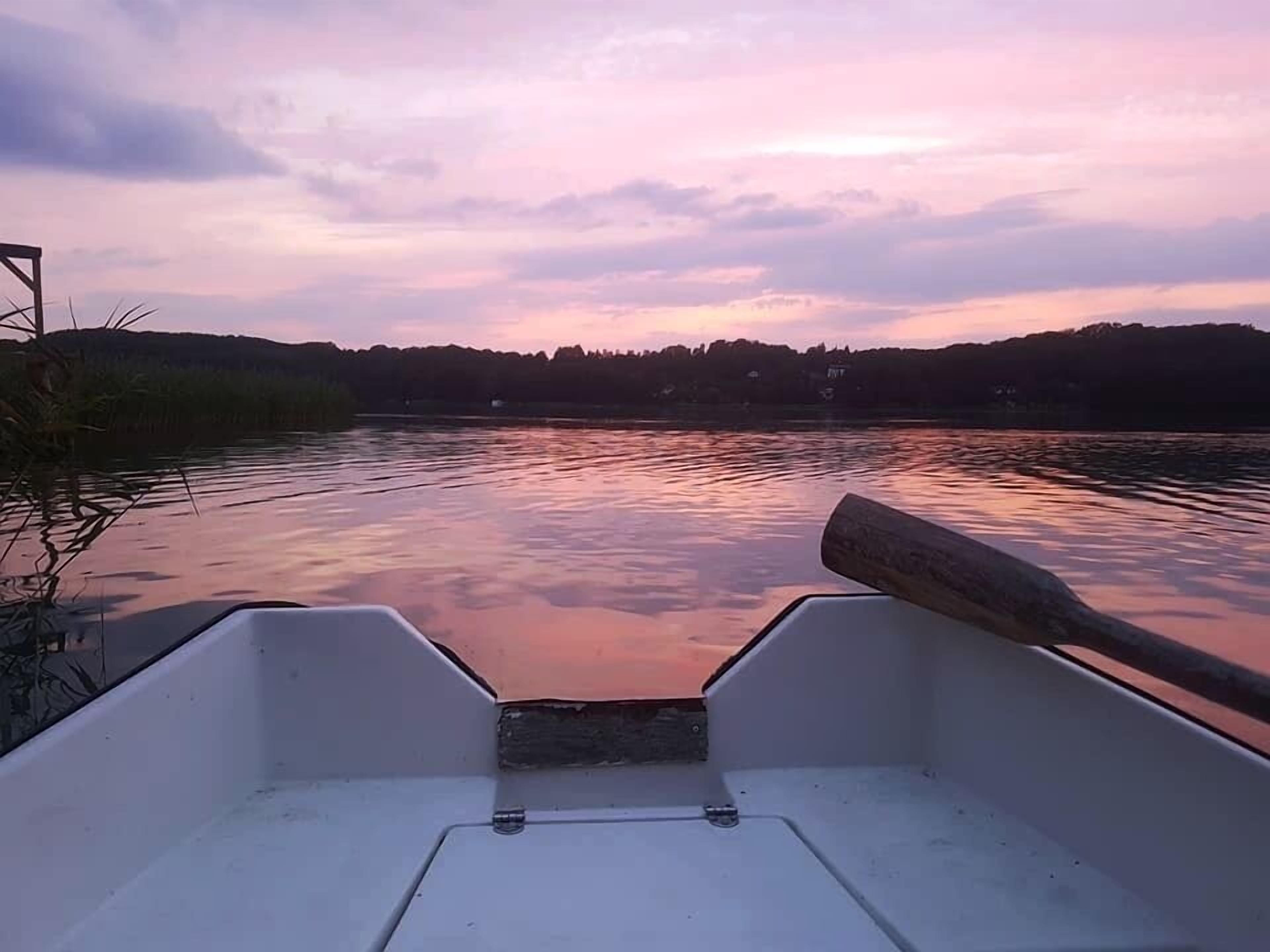 The interior of a boat with a view of a calm lake and a sunset.