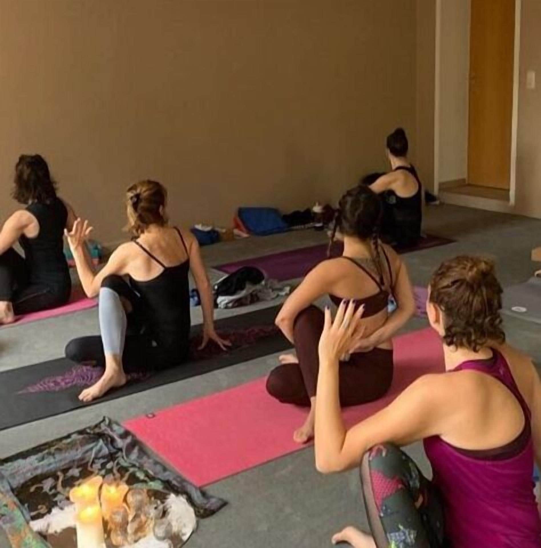 Un groupe de personnes est assis sur des tapis de yoga dans une pièce qui comporte une porte et un mur.