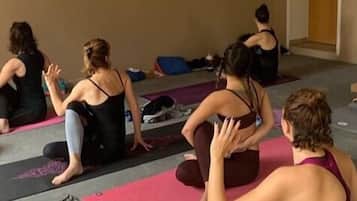Un groupe de personnes est assis sur des tapis de yoga dans une pièce qui comporte une porte et un mur.