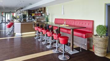 Un área de bar moderna con taburetes rojos y un banco acolchado en rojo.