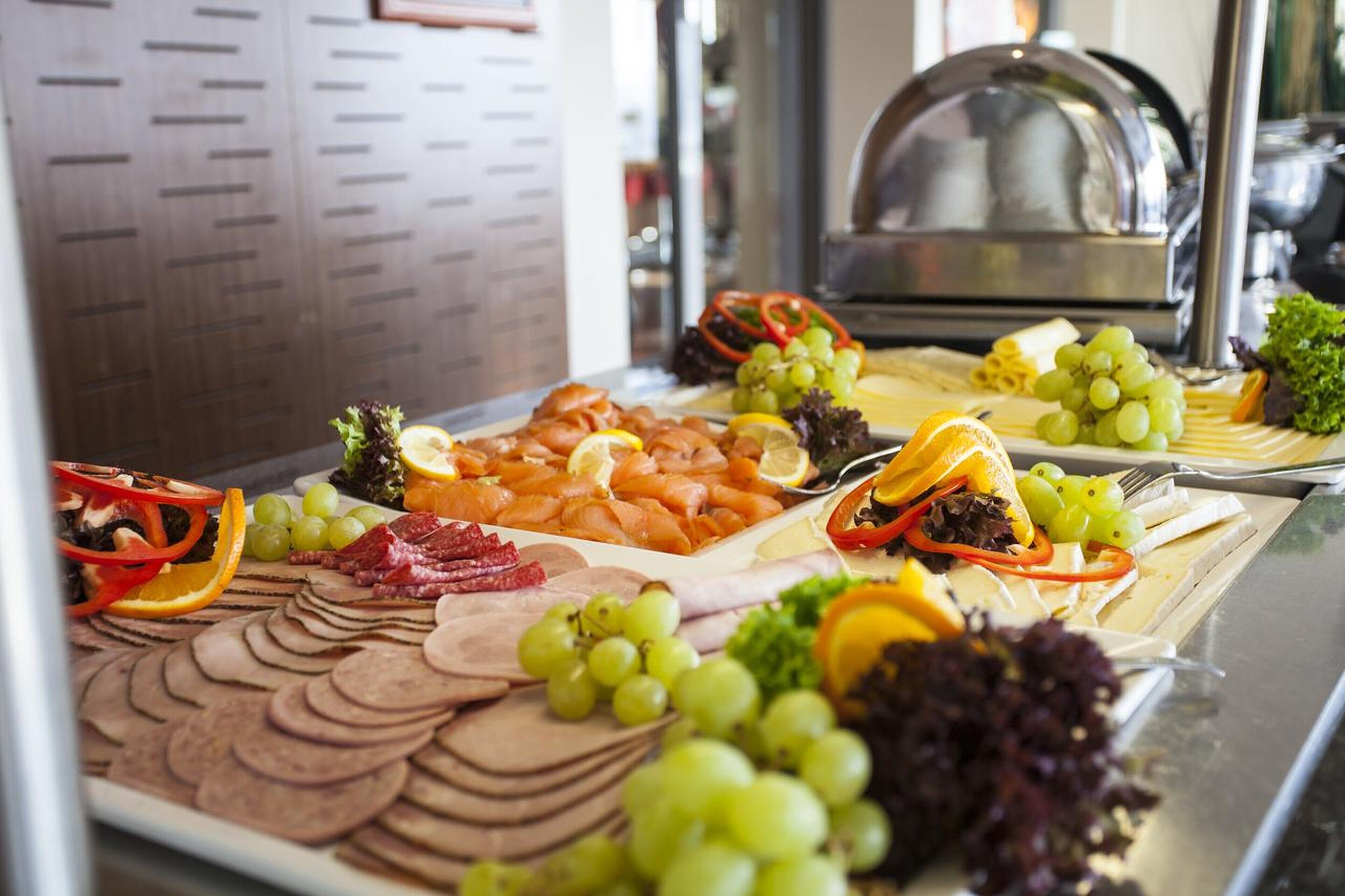 Un bufé con diversos alimentos, incluyendo carnes, quesos y frutas.