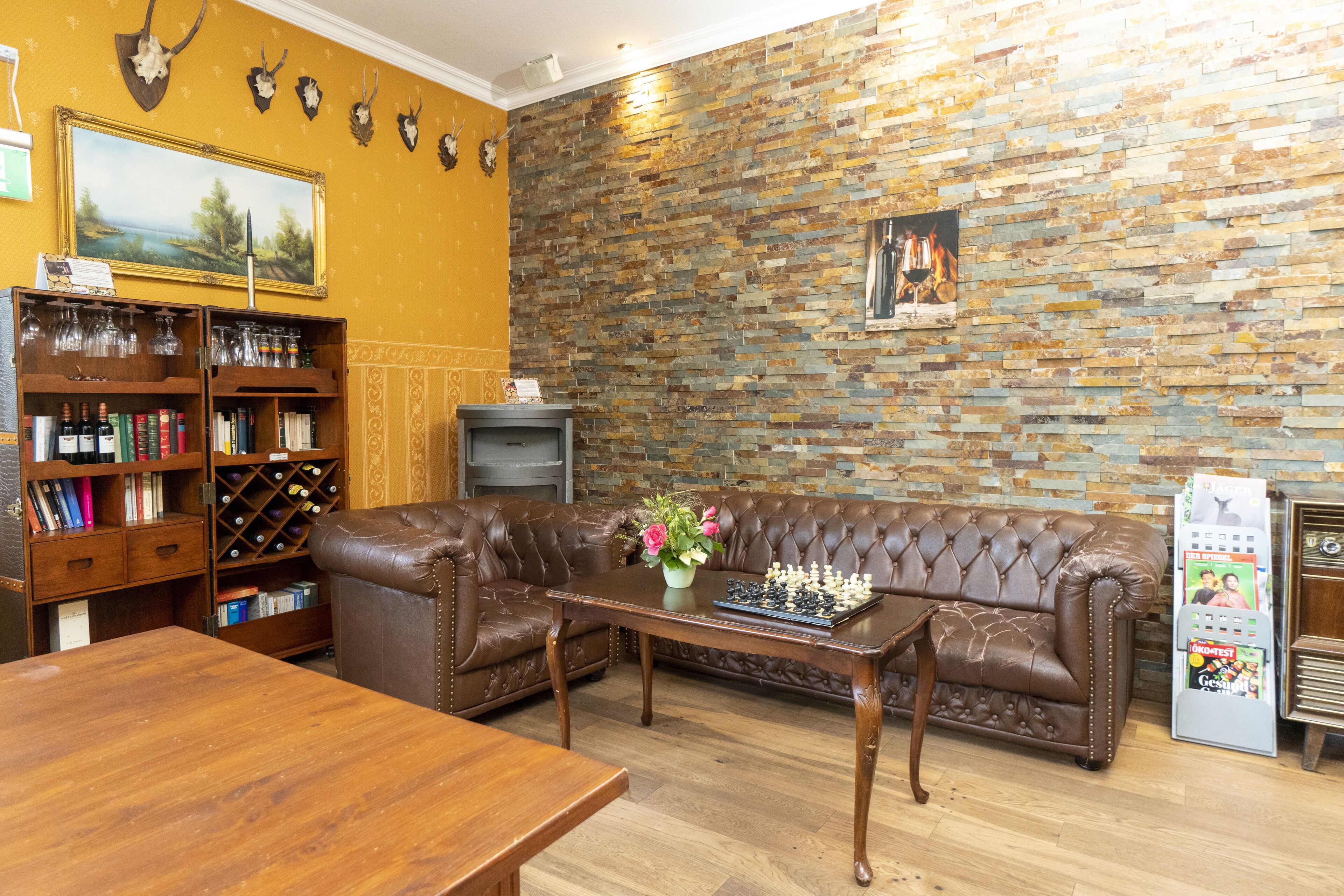Un salón acogedor con un sofá de cuero marrón, una mesa de centro de madera y una estantería llena de libros y botellas de vino.